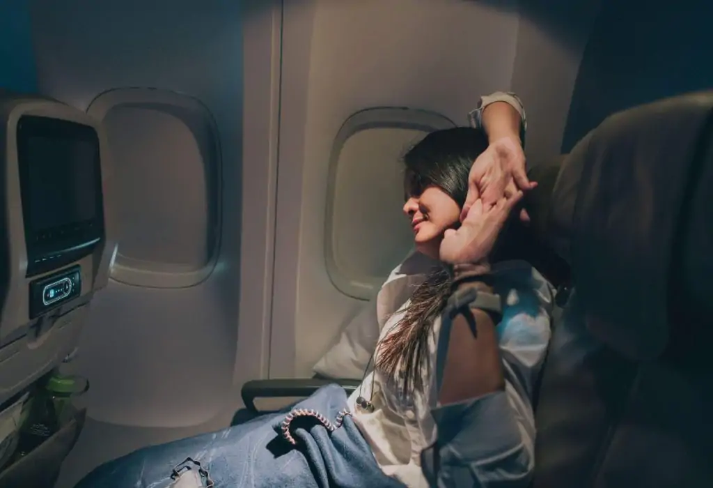Young sleepy woman passenger stretching on the airplane